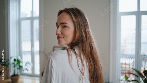 Flirting woman looking camera at home portrait. Smiling girl playing hair posing
