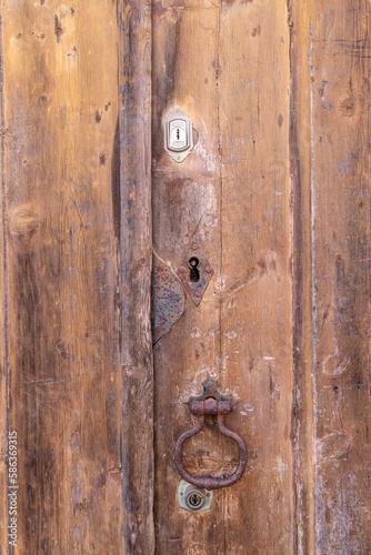 A rusted metal pull on an old wooden door. © Emily_M_Wilson