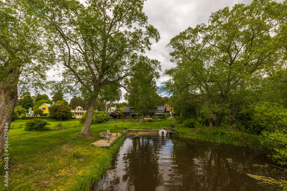 Beautiful view of village pond coast with outdoor furniture for residents. Sweden. Europe. 