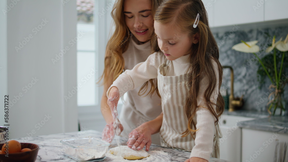 Curious kid sprinkling flour on table closeup. Single mother teach daughter bake Curious kid sprinkling flour on table closeup. Single mother teach daughter bake