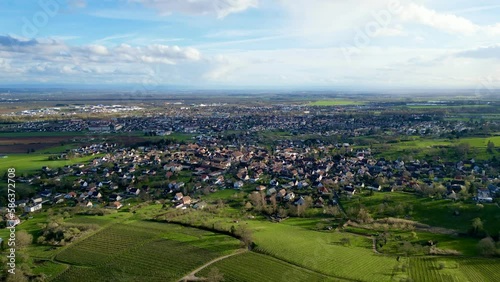 Uffholtz Winter Wonderland: Verdant Vineyards Embrace a Picturesque Village Amidst Clouds by Sunny Day Skies, Overlooking the Expansive Alsatian Plains and Distant Mountains photo