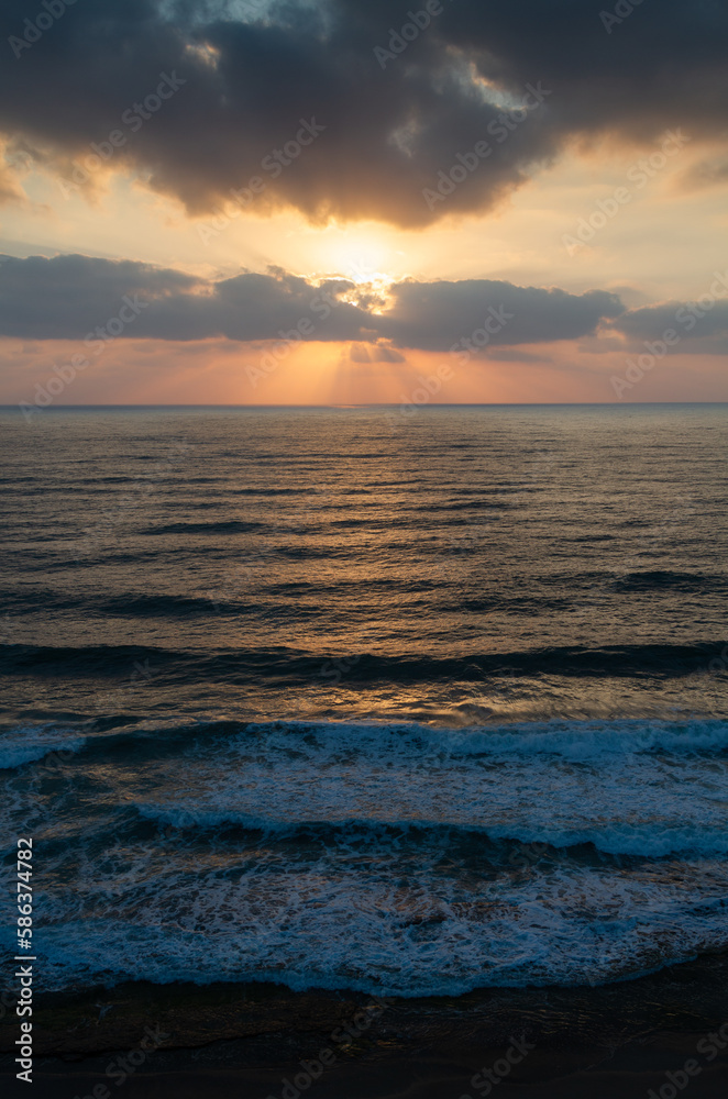 Seascape: sunset over water surface. Aerial view. Waves lapping on the shore