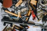 A bunch, a lot of tools scattered randomly on a table in a mechanic's workshop. Close-up photo, household junk, top view. The concept of locksmith work.