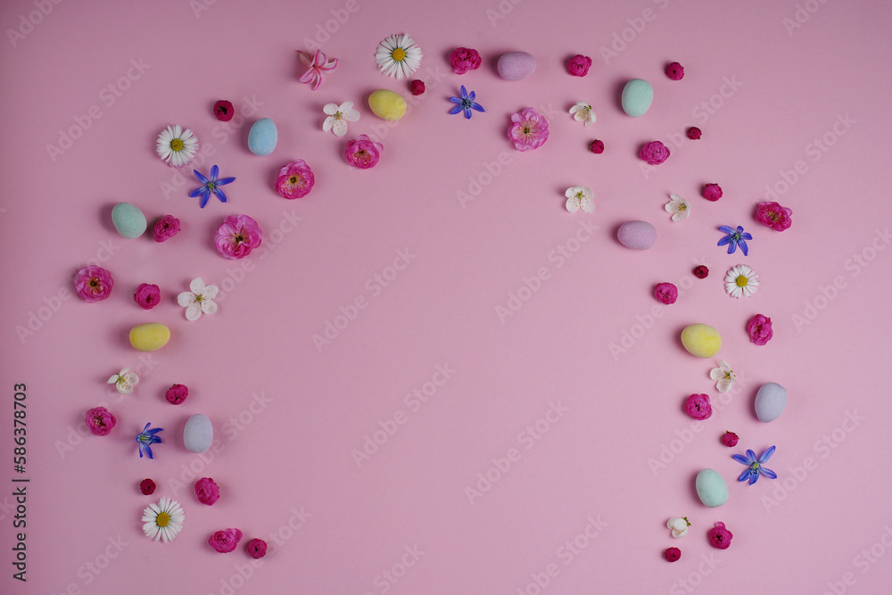 Easter concept. Top view of colorful easter eggs spring flowers on pink background with blank space