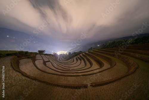Fresh paddy rice, green agricultural fields in countryside or rural area of Mu Cang Chai at night, mountain hills valley in Asia, Vietnam. Nature landscape background.