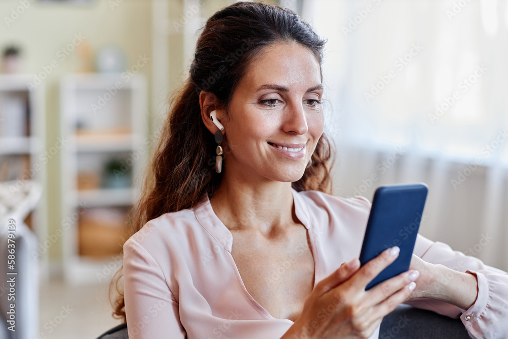 Portrait of elegant adult woman using mobile phone indoors and smiling, copy space Portrait of elegant adult woman using mobile phone indoors and smiling, copy space