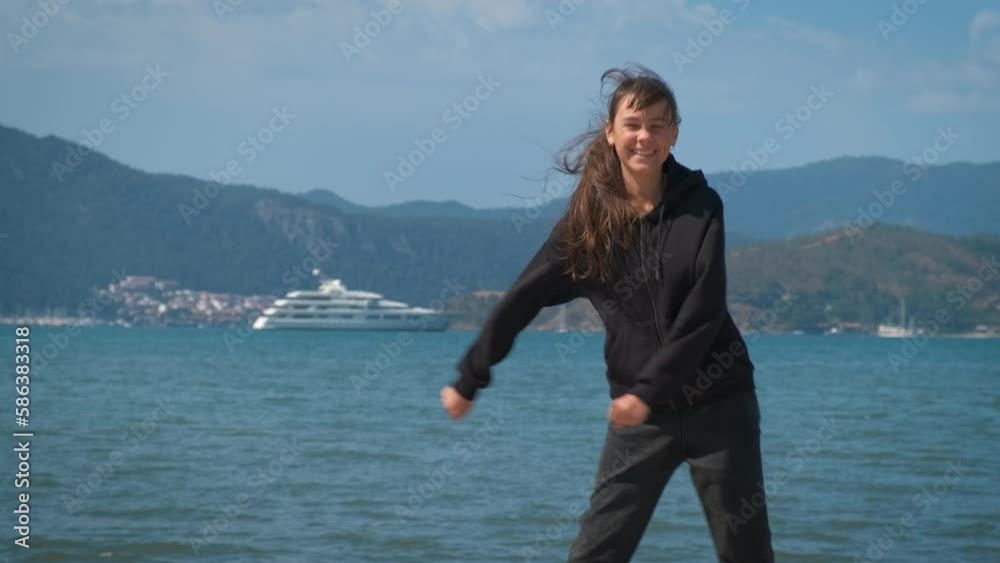 Dancing teen on piers. A pretty funny teen girl dancing on the piers against blue bay under sun. Dancing teen on piers. A pretty funny teen girl dancing on the piers against blue bay under sun.