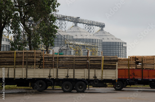 cargo trucks, transporting logging timber. with grain silos in the background