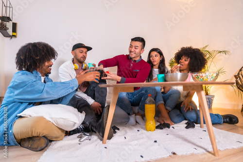 Photography Group of friends eating popcorn and laughing while watching funny movie on TV at