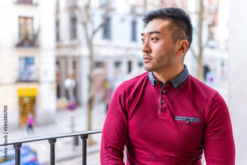 Fototapeta premium Portrait of a Chinese young man on a balcony at home, everyday situation, apartment