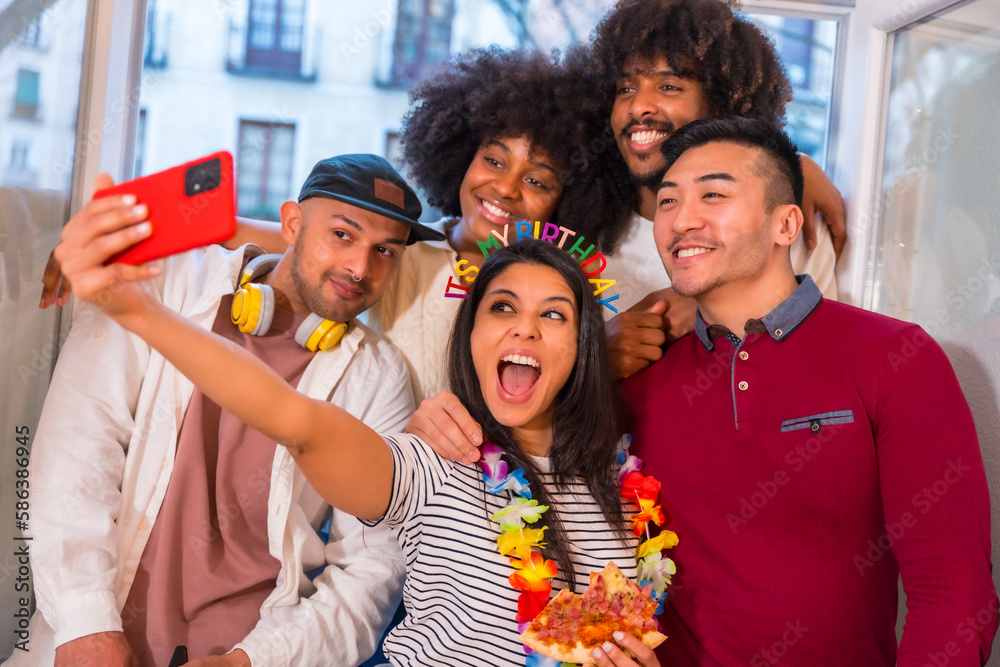 Obraz premium Portrait of a group of friends eating pizza on the terrace at home on a birthday, taking a souvenir selfie