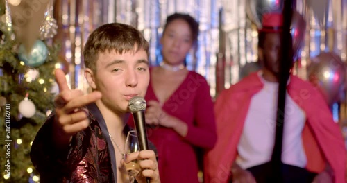 Portrait of young man showing obscene hand gesture, looking at camera during New Year celebration. A movement of hands, that is considered exceedingly offensive or vulgar in some particular cultures. 