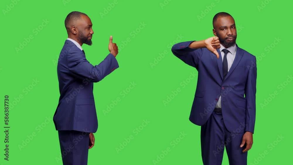 Young adult doing like and dislike symbol in studio, showing thumbs up and thumbs down sign posing over green screen backdrop. Male office worker advertising good and bad gesture. Young adult doing like and dislike symbol in studio, showing thumbs up and thumbs down sign posing over green screen backdrop. Male office worker advertising good and bad gesture.