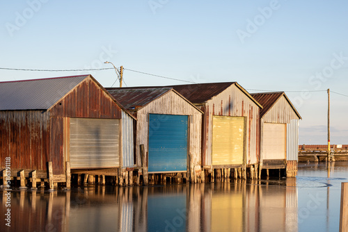 Group of four colourful boat houses on water. 