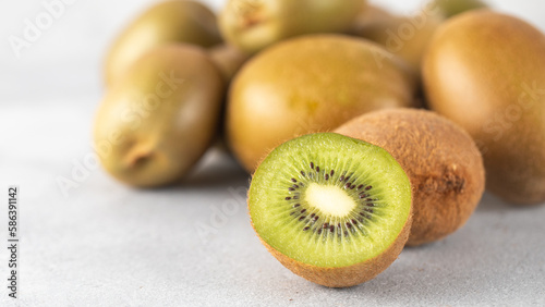 Green ripe kiwi half and whole on grey table. Place for text. Horizontal photo.