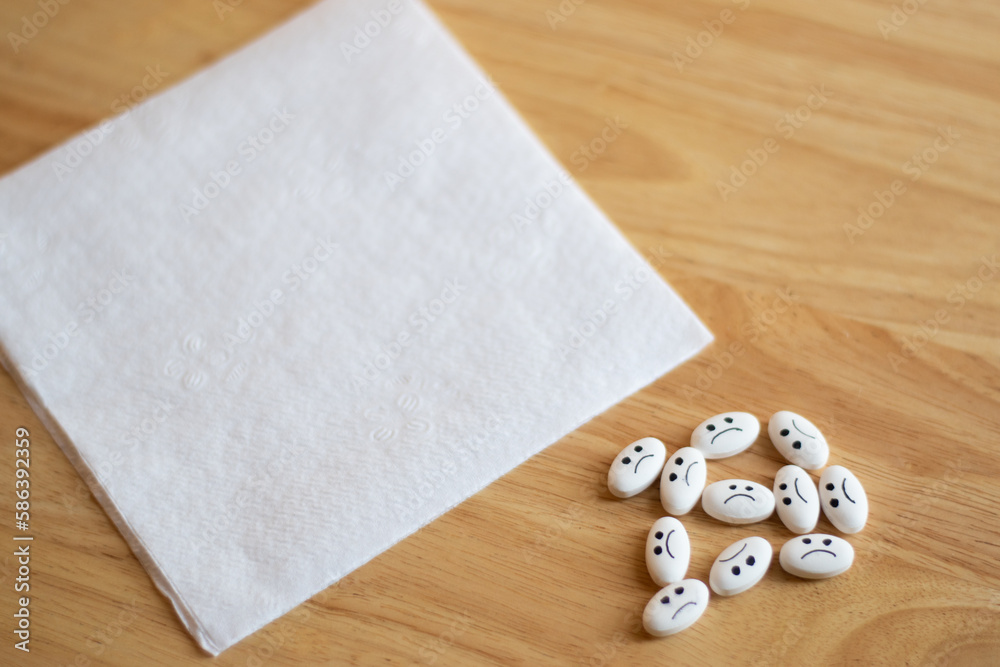 Medicine pills with sad face with depression concept and an empty letter in a wood table with focus in the pills Medicine pills with sad face with depression concept and an empty letter in a wood table with focus in the pills