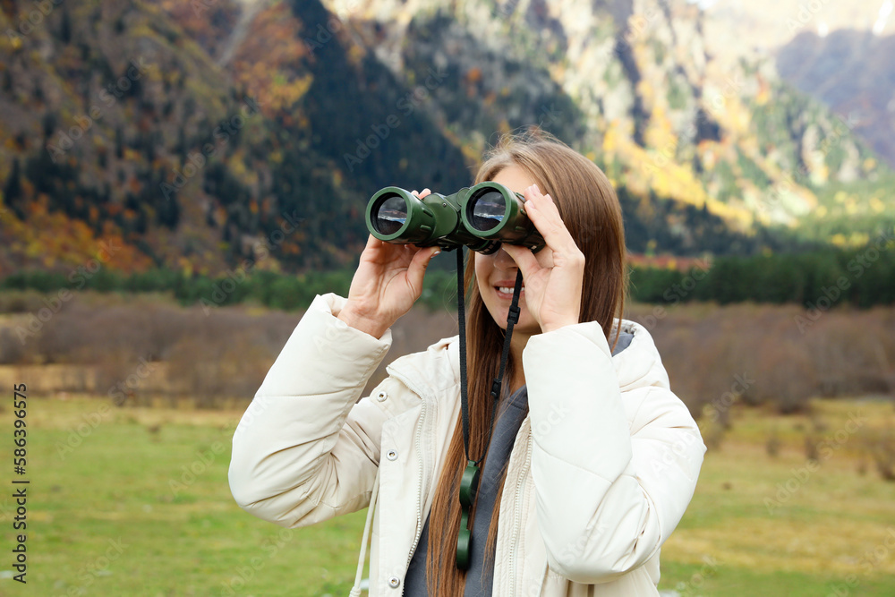 Woman looking through binoculars in beautiful mountains Woman looking through binoculars in beautiful mountains