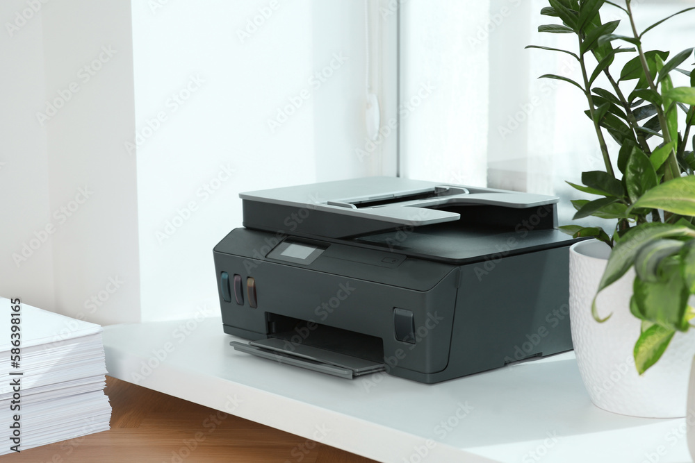 Stack of paper on wooden table near window sill with modern printer in office Stack of paper on wooden table near window sill with modern printer in office