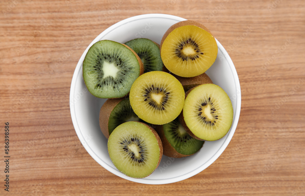 Bowl of many cut fresh kiwis on wooden table, top view Bowl of many cut fresh kiwis on wooden table, top view