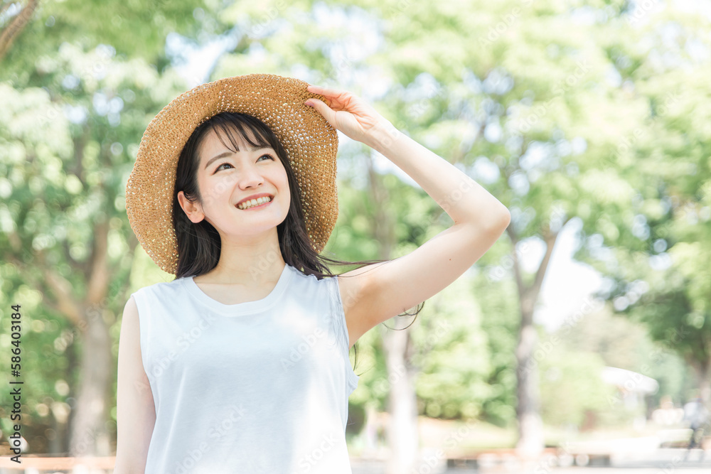 夏に麦わら帽子を被る女性（笑顔・紫外線対策）
