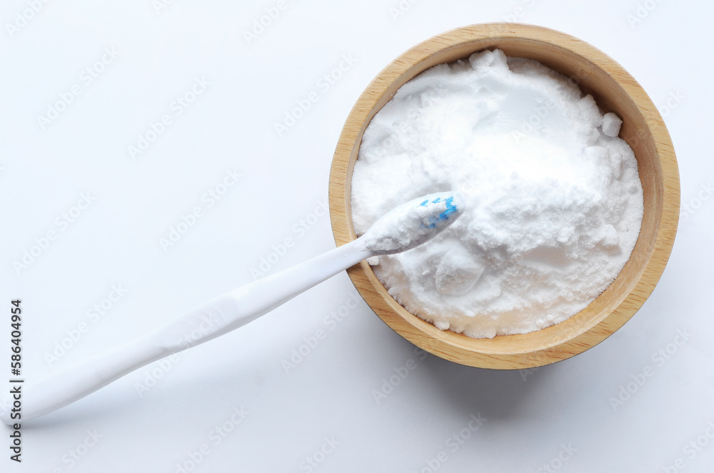 Close up of baking soda (sodium bicarbonate) in a wooden bowl with a toothbrush on white background. Teeth whitening concept. Close up of baking soda (sodium bicarbonate) in a wooden bowl with a toothbrush on white background. Teeth whitening concept.