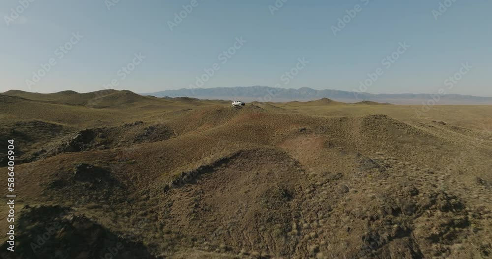 Traveler in a car stands alone on top of a canyon. Dry sand slopes. View from a drone in a summer sunny sunset Traveler in a car stands alone on top of a canyon. Dry sand slopes. View from a drone in a summer sunny sunset