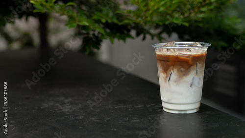 A cup of iced coffee with a clear plastic cup sits on a table in a cafe