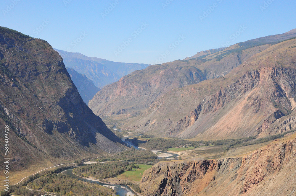 A deep canyon with a flowing meandering river on a warm autumn day.