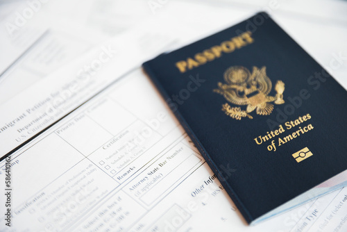 Close-up of a US passport with immigration, visa, citizenship, and travel paperwork on a wooden table