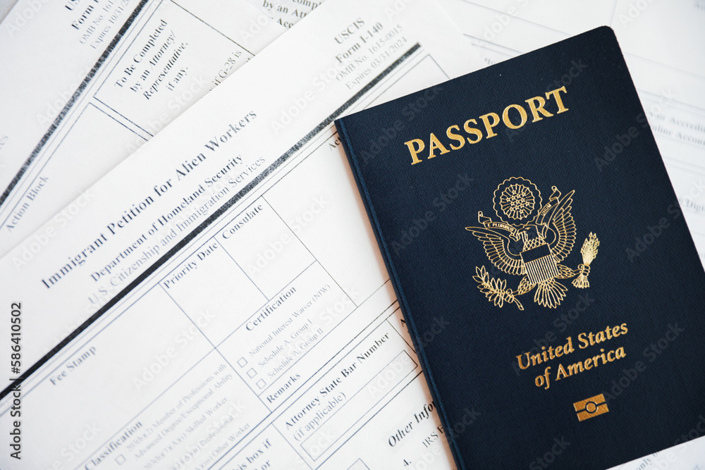 Close-up of a US passport with immigration, visa, citizenship, and travel paperwork on a wooden table Close-up of a US passport with immigration, visa, citizenship, and travel paperwork on a wooden table