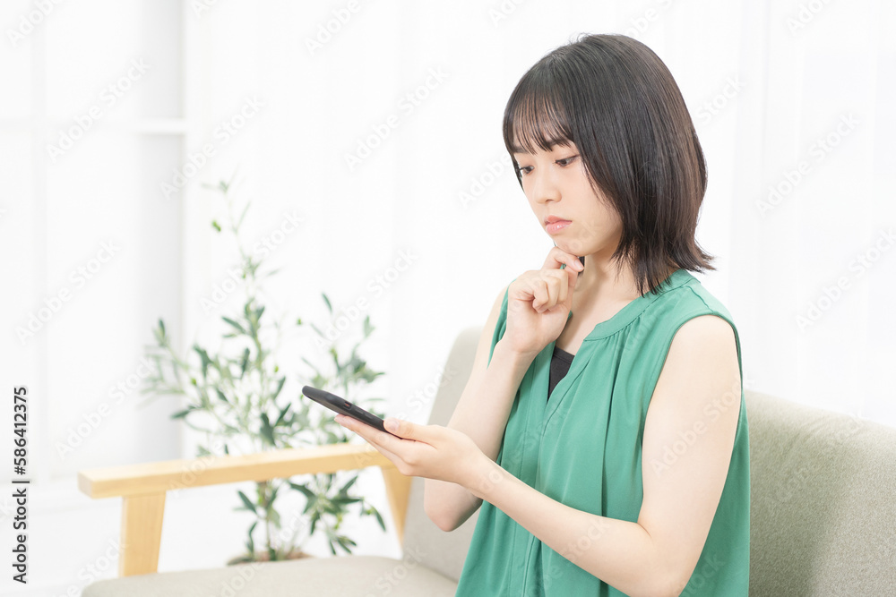 スマホを使いながら困っている若い女性 スマホを使いながら困っている若い女性