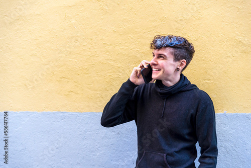 Non binary person talking on the phone outdoors.