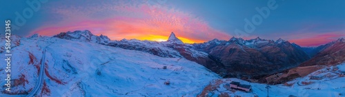 Aerial panorama view of Matterhorn mountain with amazing colorful twilight romantic sky in Switzerland. Wide establishing nature landscape sunrise or sunset of Zermatt travel ski resort in Swiss alps.
