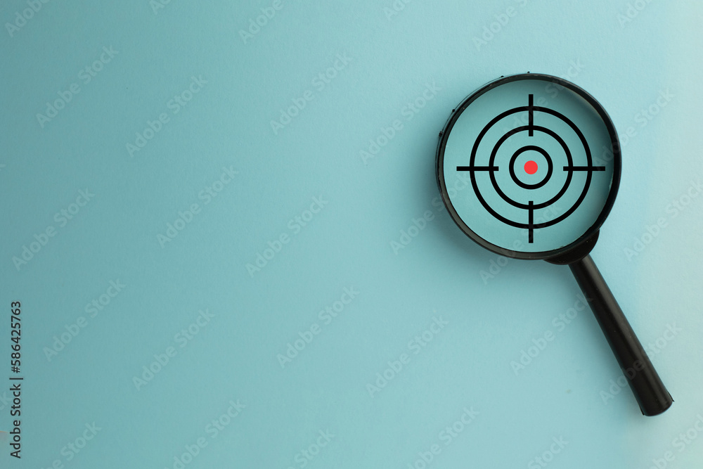 Objective Target,Goal setting or Goal objectives,Business Target or mission,Purposefulness,challenge concept.Magnifying glass with Target icon on blue background with copyspace. Objective Target,Goal setting or Goal objectives,Business Target or mission,Purposefulness,challenge concept.Magnifying glass with Target icon on blue background with copyspace.