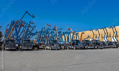 Construction machinery for rent. Lifts with raised platforms and cargo trucks are at the industrial court yard