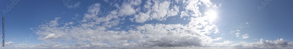 white fluffy clouds with sun on blue sky background. wide panoramic view. white fluffy clouds with sun on blue sky background. wide panoramic view.