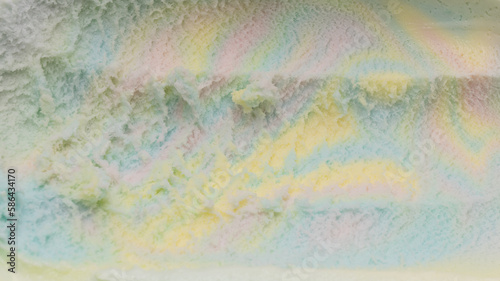 Close-up of rainbow-flavored ice cream scooped out of the container until it forms a groove.