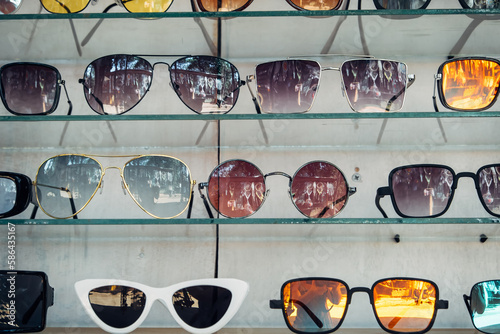 A showcase with a large number of fashionable sunglasses of different shapes. Background for traveling to sunny countries