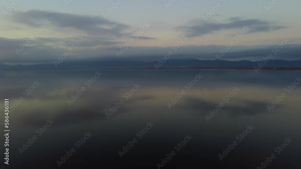 Aerial over lake and mountains with sky reflection at dusk Aerial over lake and mountains with sky reflection at dusk