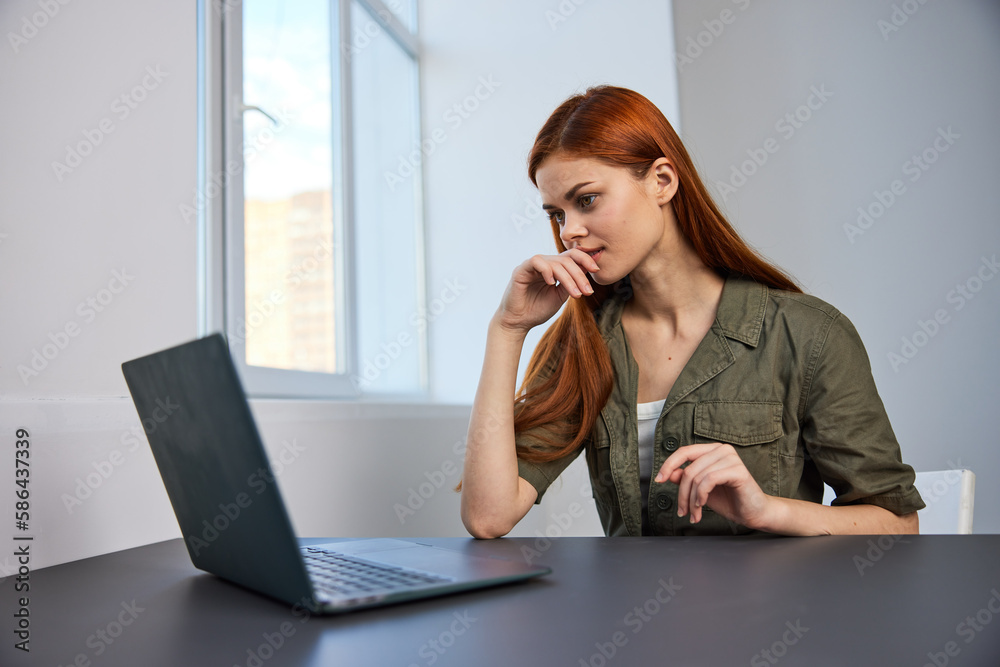 portrait of a red-haired woman looking puzzled at a laptop portrait of a red-haired woman looking puzzled at a laptop