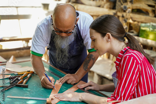 Team of leathers maker is drawing a design on leather in leather workshop.