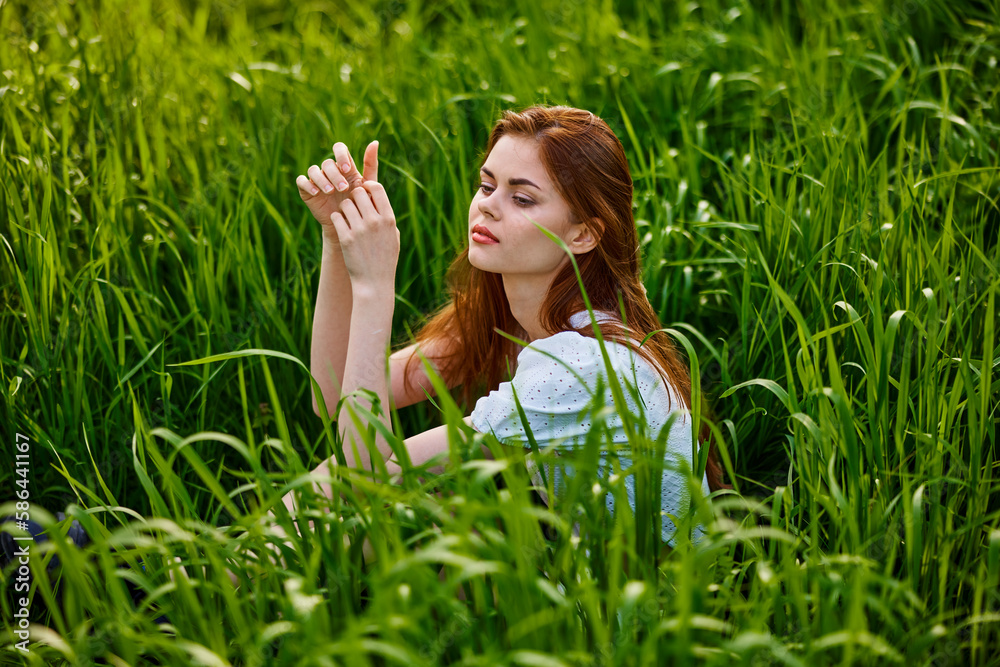 sad woman sitting in tall green grass on a sunny day sad woman sitting in tall green grass on a sunny day