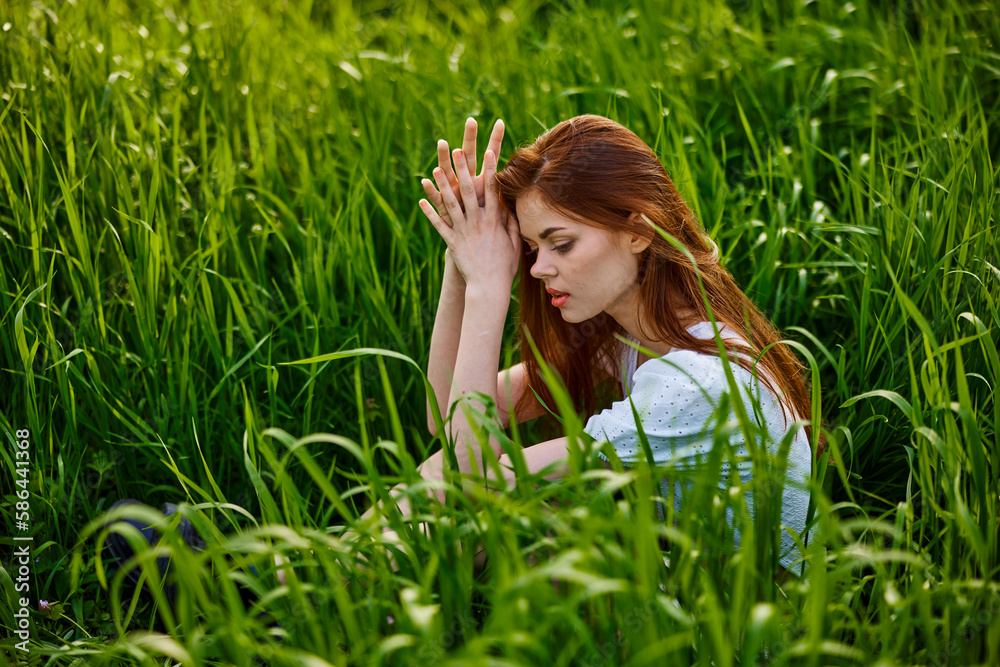 sad woman sitting in tall green grass on a sunny day sad woman sitting in tall green grass on a sunny day