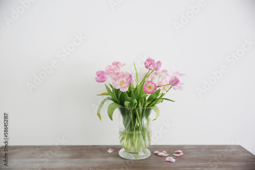 Bouquet of pink tulips in vase on wooden table