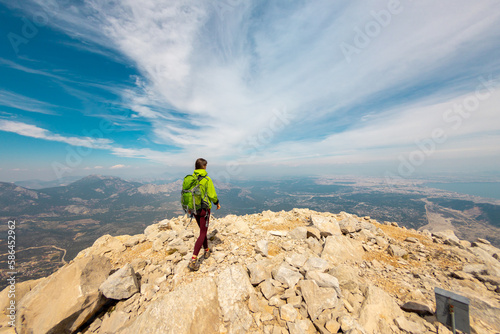 Woman climber with a backpack and a helmet in the mountains. A girl with a backpack walks along a mountain range. adventure and mountaineering concept.