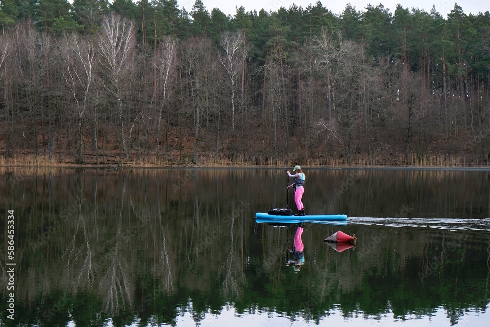 A woman is paddling on a SUP board on lake Borowno Wielkie, Kociewie, Pomerania, Poland