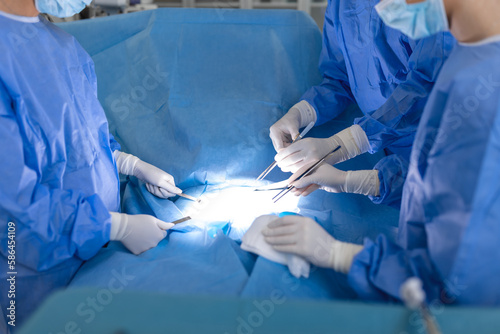Surgery operation. Group of surgeons in operating room with surgery equipment. Medical background, selective focus. Surgeon team working together while operation