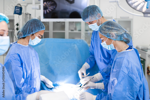 Team of Professional surgeon, Assistants and Nurses Performing Invasive Surgery on a Patient in the Hospital Operating Room. Surgeons Talk and Use Instruments. Real Modern Hospital.