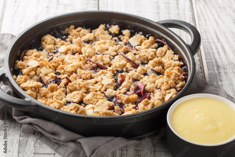 Berry fruit crumble baked with apples and blueberries served with vanilla sauce close-up in a pan on the table. Horizontal Berry fruit crumble baked with apples and blueberries served with vanilla sauce close-up in a pan on the table. Horizontal