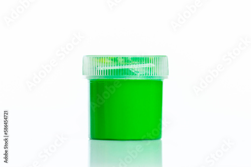 Plastic jar with green gouache. Creativity, hobby and arts. Isolated on white background with reflection. Close-up.
